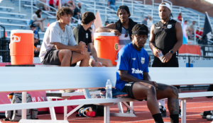 Soccer player sitting on bench.